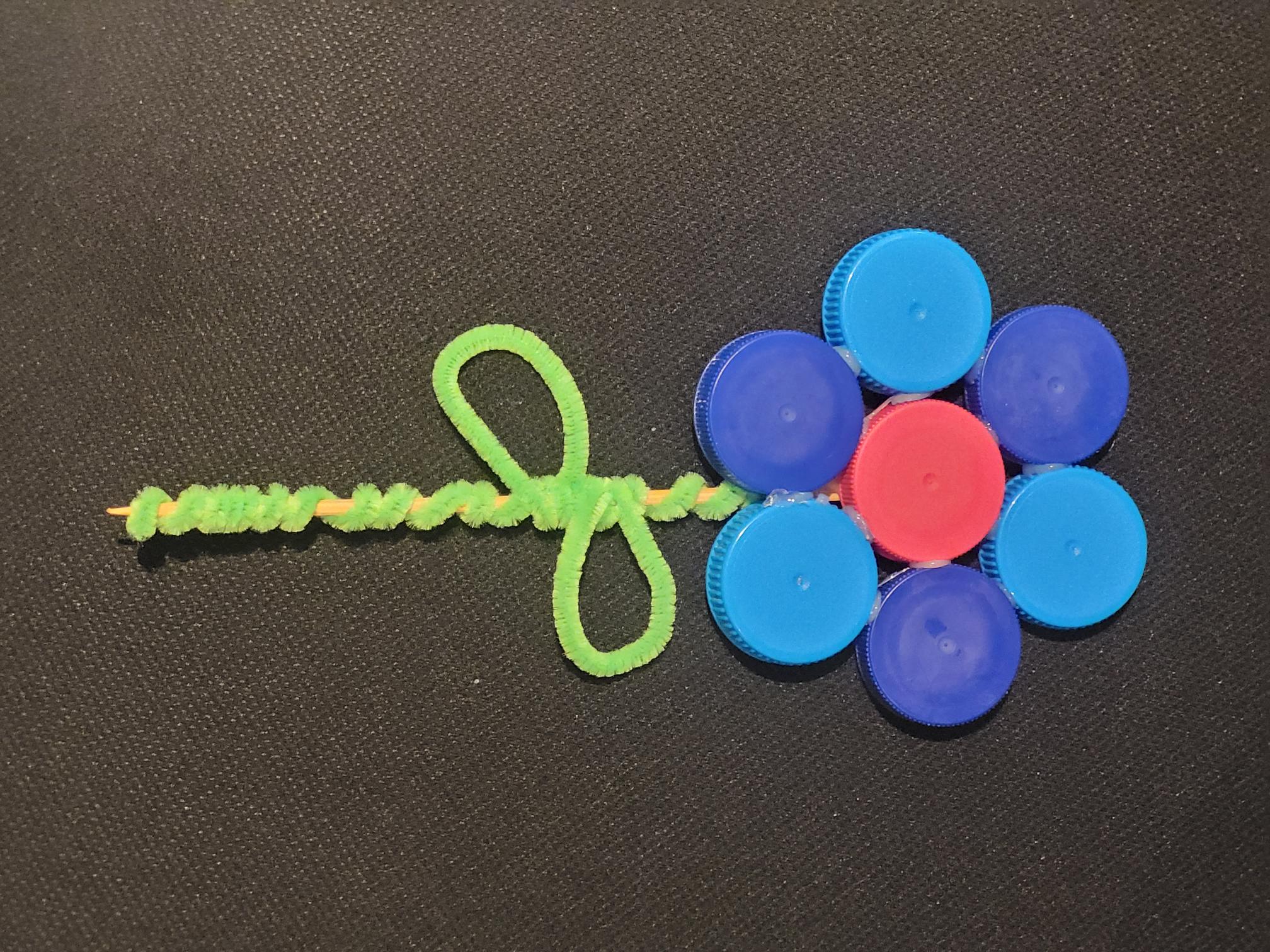 A flower made out of blue bottle capes and a green pipecleaner for the stalk.